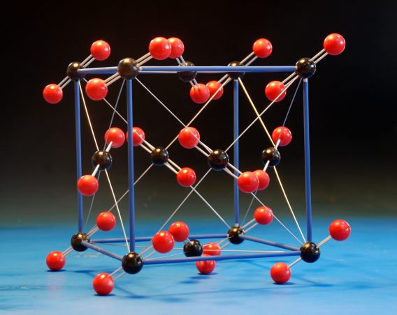 A large crystal structure model of carbon dioxide, CO2, made with wood balls and aluminium rods, with a highlighted unit cell