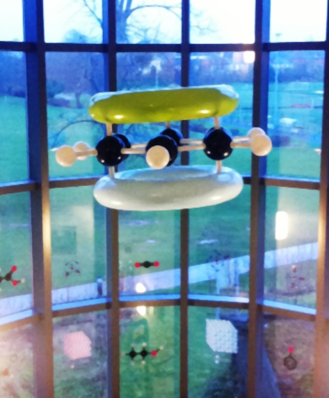 A giant molecular model of benzene with pi orbitals hanging from a ceiling